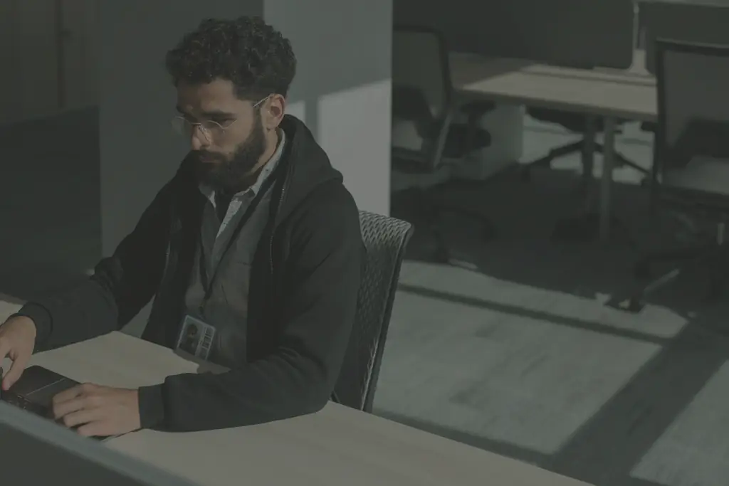 A man working on a laptop at his desk in a quiet office